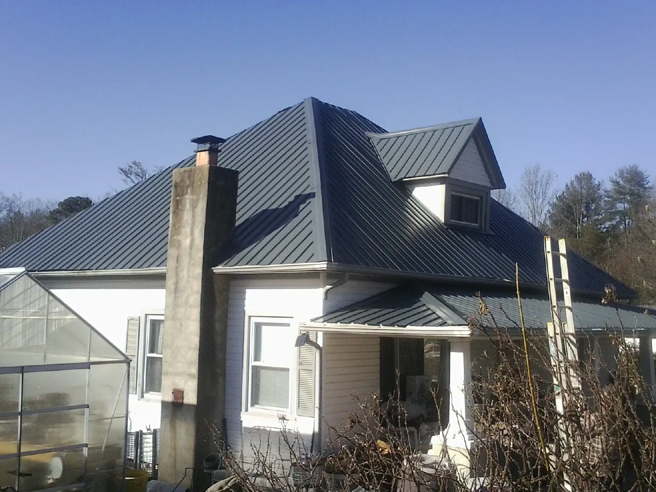 Dark blue standing seam metal roof on a white farmhouse with dormer — Slate & Tile Roof Repair by Roofing Brothers in Jenkinsburg