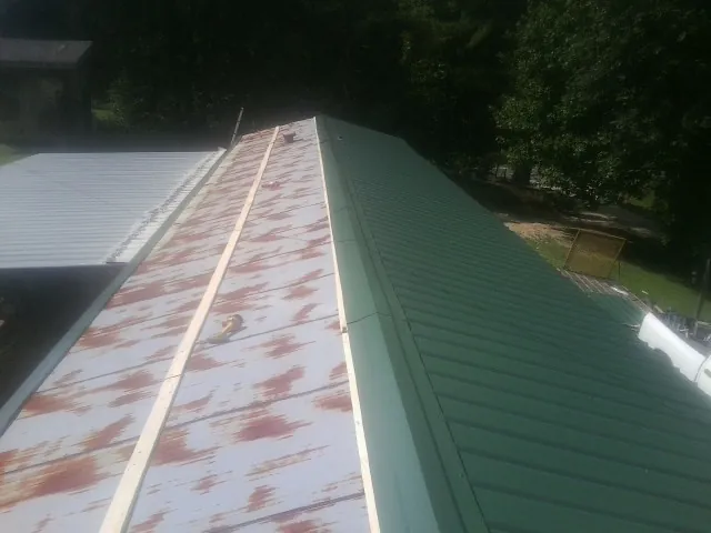 Old rusted panels beside newly installed green metal roofing — Wind Damage Roof Repair by Roofing Brothers in Jenkinsburg