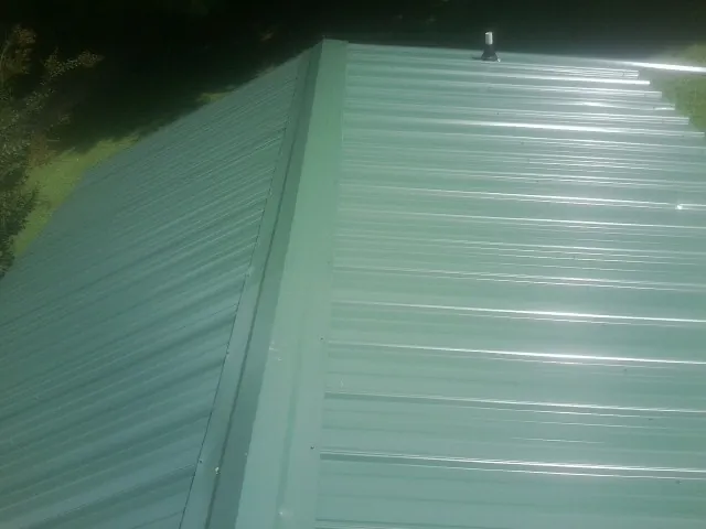 New green metal panels meeting at the ridge of a roof — Flat Roof Repair work by our crew in Jenkinsburg