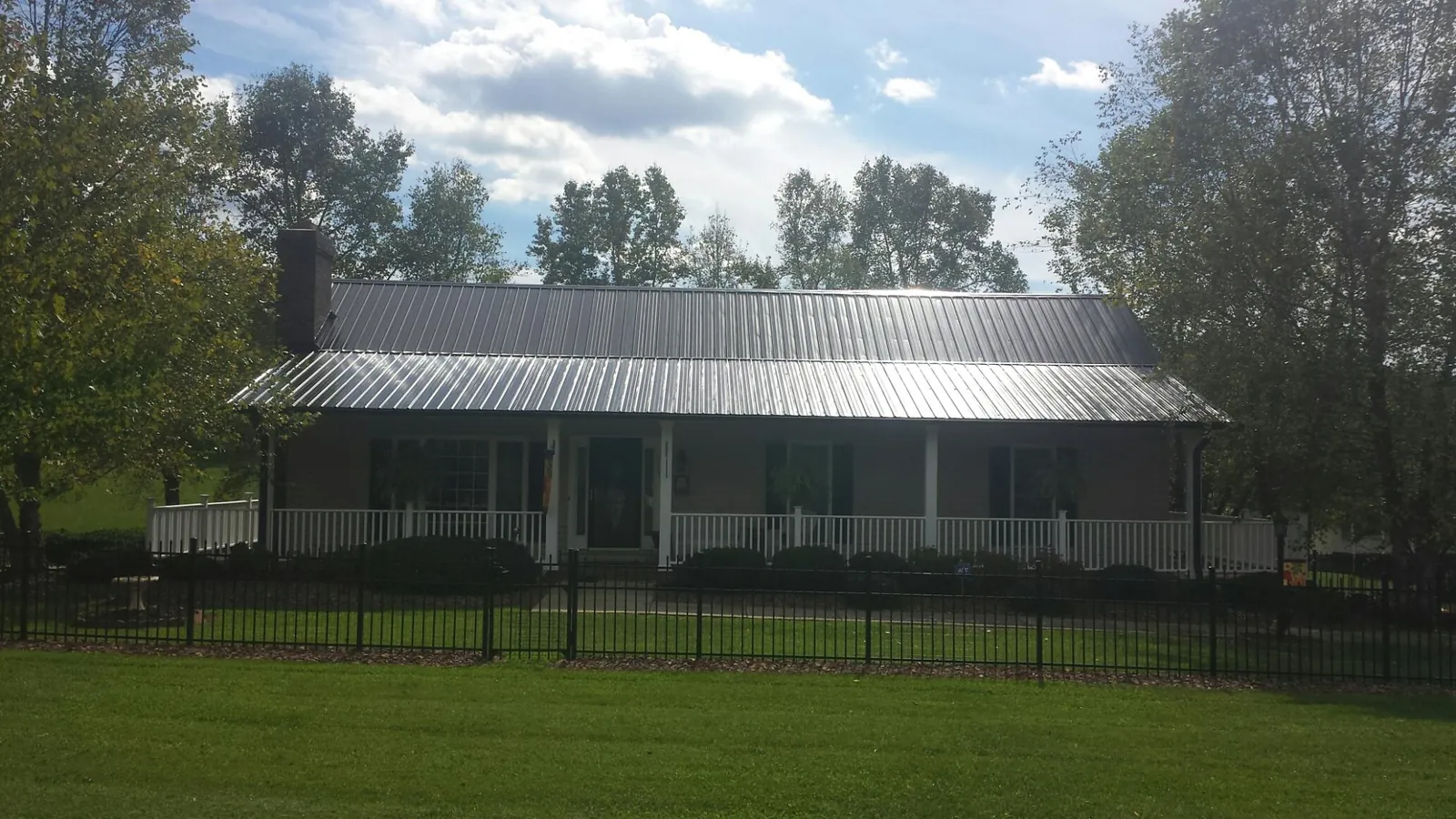 Gray metal roof on a brick ranch with a full width front porch — Gutter Guard Installation work by our crew in Jenkinsburg