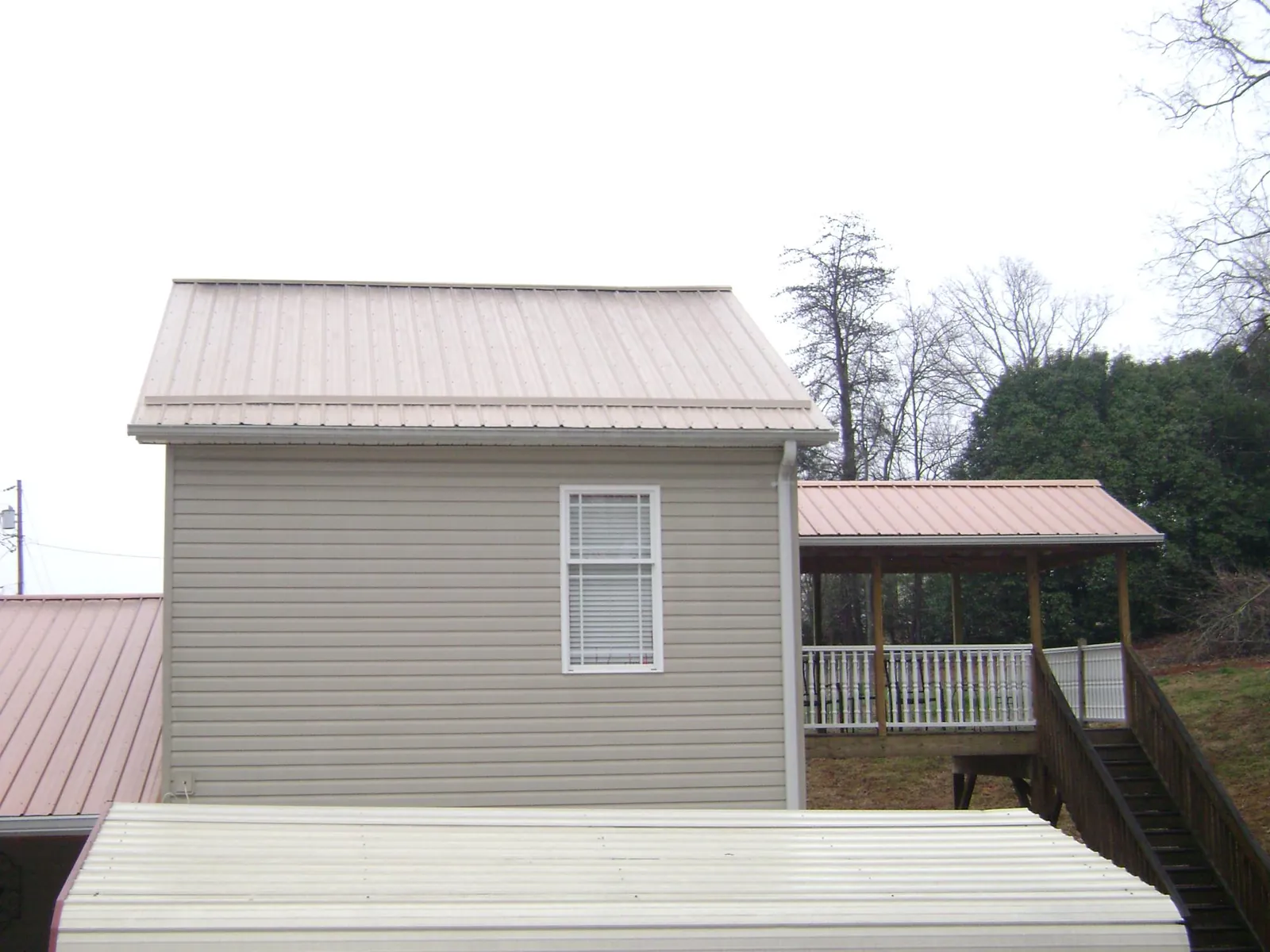 Tan metal roofs on a two story addition and attached porch, from a Roof Replacement job in Jenkinsburg