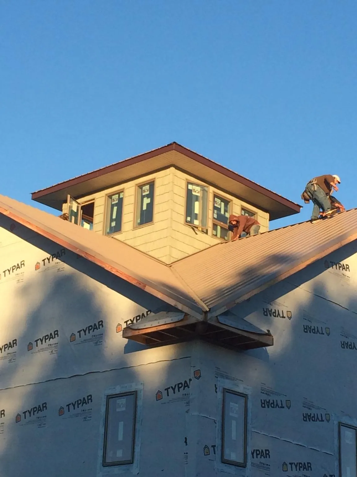 Roofers working around a rooftop cupola on a new metal roof at sunset — Roof Waterproofing in Jenkinsburg by Roofing Brothers